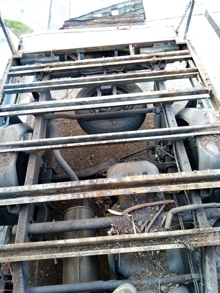 Vista detallada bajo el chasis de la plataforma de un camión en Panamá, mostrando vigas de acero oxidadas y la necesidad de mantenimiento de soldadura.