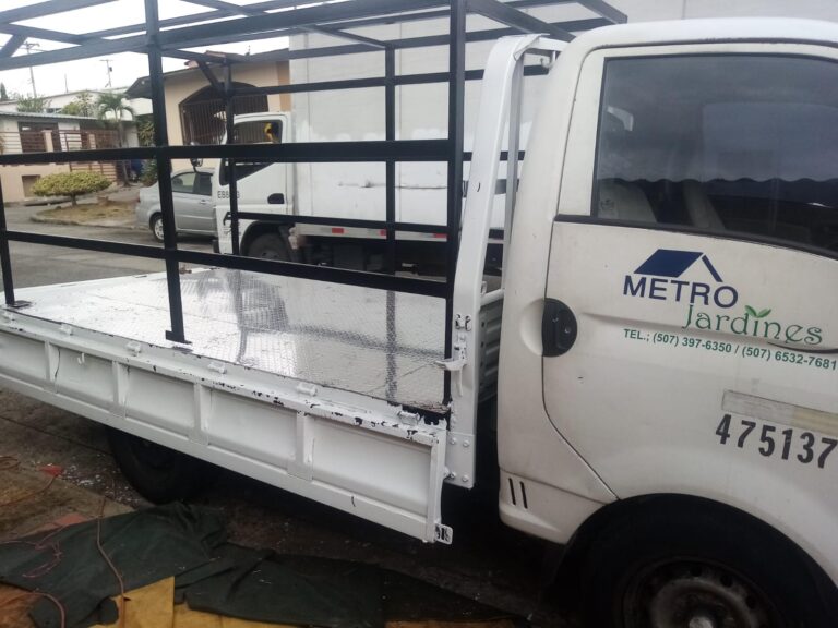 Perfil lateral de un camión de servicio blanco METRO Jardines en Panamá, con la nueva jaula de acero y piso de aluminio instalados por nuestro equipo de soldadura.